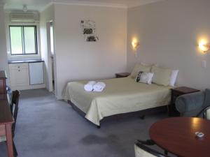 a bedroom with a bed with two towels on it at Elite Motor Inn in Armidale