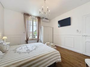Un dormitorio blanco con una cama grande y una lámpara de araña. en Charmante maison 2 chambres avec cour et jardin, en Sainte-Savine