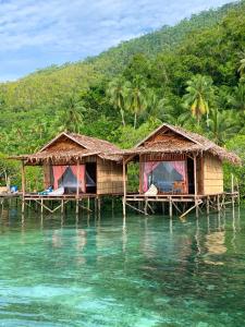a couple of huts on a pier in the water at Seahorse Homestay in Pulau Mansuar