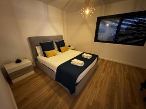 a bedroom with a bed with yellow pillows and a window at Sky & Ocean in Calheta