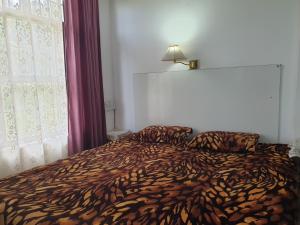 a bedroom with a bed with a animal print blanket at Greenwood Cottage in Mukteswar