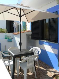 una mesa negra con sillas blancas y sombrilla en Casa Azul, en Albufeira