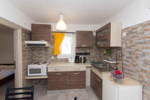 a small kitchen with wooden cabinets and a microwave at PAROS APARTMENT MELAS b1 in Parikia
