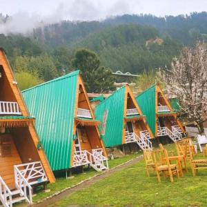 eine Reihe von Hütten mit Stühlen und Tischen in der Unterkunft Kaira huts in Manali