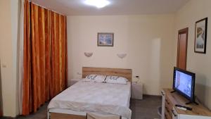 Un dormitorio con una cama y un televisor de pantalla plana. en Nestinarka beach studio, en Tsarevo