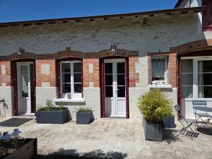 a brick building with white doors and potted plants at La Renardière in Bourges