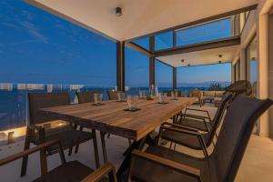a dining room with a large wooden table and chairs at Villa Serena Luxury Seafront Escape with Pool in Privlaka