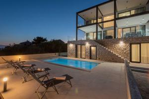 a house with a swimming pool in front of it at Villa Serena Luxury Seafront Escape with Pool in Privlaka