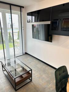 a living room with a glass table and a chair at Apartament Modesta Przy Aquaparku Reda in Rumia