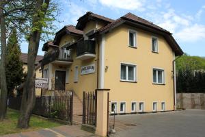 una casa amarilla con una puerta y un árbol en Willa Preludium, en Gdansk