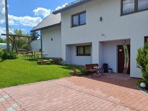 a white house with a brick patio at Pokoje pod Śnieżnicą in Kasina Wielka