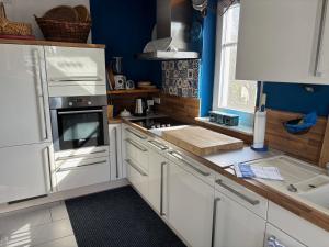 a kitchen with white cabinets and blue walls at Ferienwohnung HeilbadOase in Erwitte