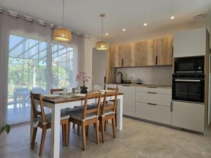 a kitchen with a table and chairs and a kitchen with white cabinets at Cocoon Luberon in Lauris
