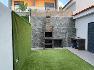 a backyard with a brick fireplace and green grass at homeSilvaSanches in Quinta do Conde