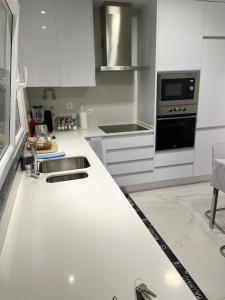 a white kitchen with a sink and a stove at homeSilvaSanches in Quinta do Conde +10 photos
