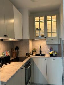 una cucina con mobili bianchi e un lavandino di Fewo Schröder - Pier 5 - Strandkorb am Meer - seitlicher Meerblick - inklusiv Bettwäsche und Handtücher a Büsum