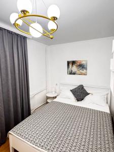 a bedroom with a bed and a chandelier at 2 комнатная в историческом центре Наурызбай батыра 41 in Almaty