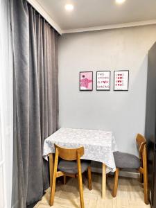 a dining room table with two chairs and a curtain at 2 комнатная в историческом центре Наурызбай батыра 41 in Almaty