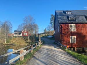 a road next to a red house and a bridge at Sweet guest house with a view in Sävsjö