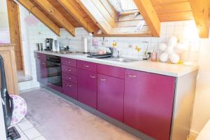 a kitchen with purple cabinets and a sink at Familienferienwohnung Buggi-Näschtli in Grafenhausen