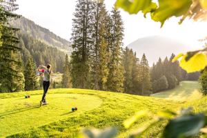 a woman standing on a grassy hill with a soccer ball at ALPSTAY Platzhirsch - Ski-In & Ski-Out in Bad Kleinkirchheim