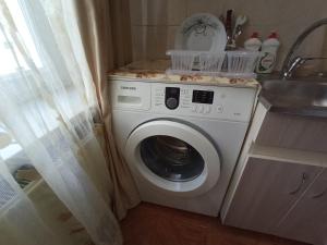 a washing machine in a kitchen next to a sink at Уютная квартира in Mekhrably
