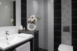 a bathroom with a sink and a vase with flowers at Hotel & Spa Gil de France Cap d'Agde in Cap d'Agde