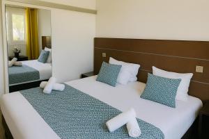 a hotel room with two beds with blue and white pillows at Hotel & Spa Gil de France Cap d'Agde in Cap d'Agde
