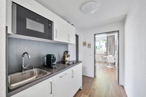 a kitchen with a sink and a microwave above a counter at Ankerherz Appartements bei Blankenese in Hamburg
