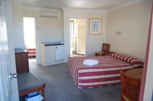 a bedroom with a bed with a striped blanket at Elite Motor Inn in Armidale