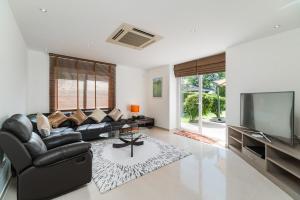 a living room with a black leather couch and a flat screen tv at Luxury Pool Villa 604 4BR 10 Persons BBQ in Nong Prue