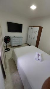 a bedroom with a white bed and a tv at Ap Família Shopping Riomar e Praia in Aracaju