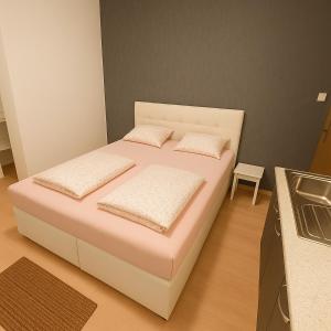 Cama blanca en habitación con cocina en City Rooms, en Viena