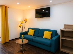 a living room with a blue couch with yellow pillows at Hotel & Spa Gil de France Cap d'Agde in Cap d'Agde