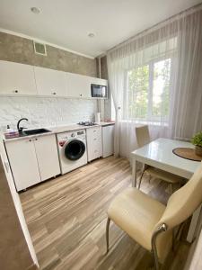 una cucina con armadi bianchi, tavolo e lavandino di Стильные апартаменты со свежим ремонтом на ЖД вокзале a Qostanay