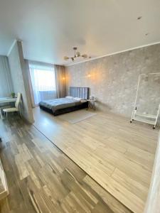 una grande camera con un letto e un pavimento in legno di Стильные апартаменты со свежим ремонтом на ЖД вокзале a Qostanay Altre 2 foto