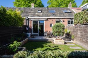 a garden with a brick house with a patio at Vakantiehuisje De Barones in Middelburg