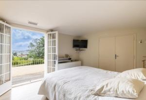 a bedroom with a bed and a large window at Havre de paix -Élégante villa avec piscine au cœur d'un écrin de verdure in Vence +25 photos