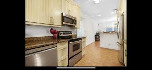 Una cocina con electrodomésticos de acero inoxidable y gabinetes de madera. en Newly Renovated Fort Lauderdale Pool Home 3BR and 3 and a half baths, en Fort Lauderdale