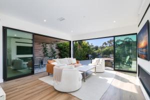 una sala de estar con muebles blancos y grandes ventanas de cristal. en Luxury Pool Haven Scenic Views and Summer Fireworks, en San Diego