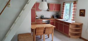 a kitchen with red cabinets and a wooden table at Cottage Bergen NH in Bergen