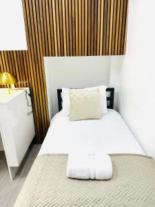 a bedroom with a white bed with a wooden headboard at Westferry Two-Bedroom Deluxe Apartment in London