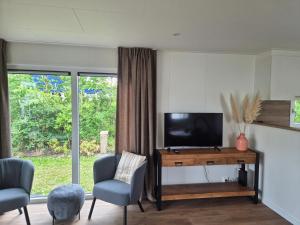 a living room with a television and two chairs at Eldorado in Petten