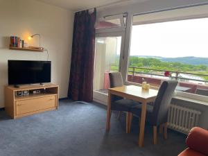 a living room with a table and a television and a window at Panoramalounge 712 in Lahnstein