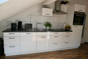 a kitchen with white cabinets and a sink at Ferienwohnung David in Ochsenhausen