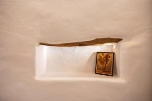 a picture hanging on a wall with a branch at Aegean Blue in Ios Chora