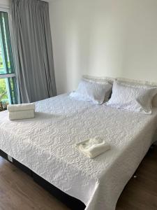 a white bed with white sheets and pillows on it at Studio Ilha Pura Barra Olímpica in Rio de Janeiro