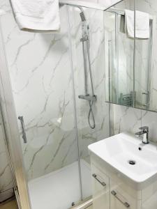 a white bathroom with a shower and a sink at Westferry Two-Bedroom Deluxe Apartment in London
