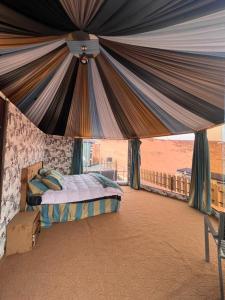 1 dormitorio con 1 cama debajo de una tienda de campaña en Rum Awaad luxury camp, en Wadi Rum