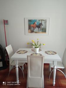 a white dining room table with two chairs and a painting at Appartamento al mare in Eraclea Mare +10 photos
